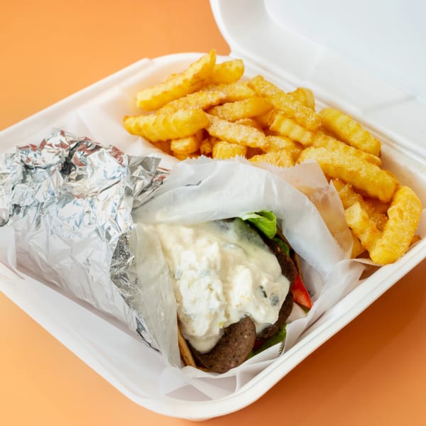 Hip Hop Fish and Chicken's burger with white sauce and fries in a takeout container.